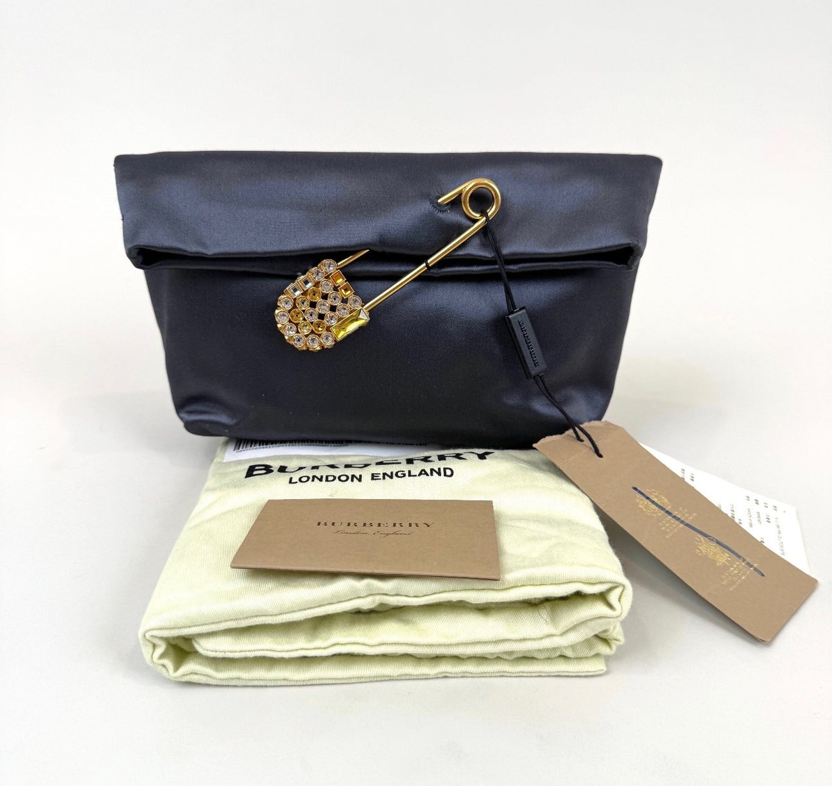 Burberry Grey Silk Satin Clutch featuring a large gold-tone safety pin embellished with crystals